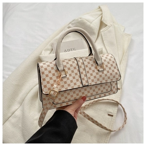 Detail of cream crossbody bag with geometric patterns, gold hardware and top handle
