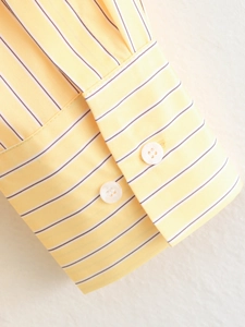 Detail of yellow striped poplin shirt cuff featuring delicate white buttons and stitching