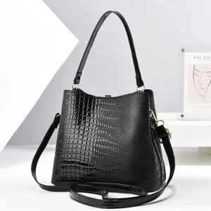 Close-up of black crocodile pattern patent leather bucket bag with gold metal hardware