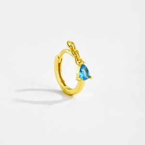Detail of gold hoop earring featuring a blue teardrop stone and elegant chain decoration