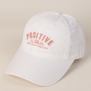 Détail de la casquette blanche avec broderie POSITIVE rose et motif d'ours polaire