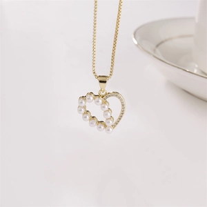 Collier cœur plaqué or avec perles et zircons sur fond blanc épuré