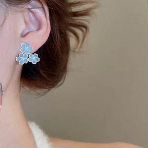 Gros plan détaillé de boucles d'oreilles fleurs en résine bleue portées par un mannequin