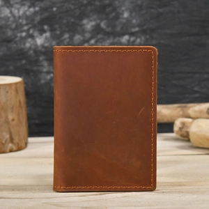 Close-up of brown crazy horse leather wallet with visible stitching on wood surface