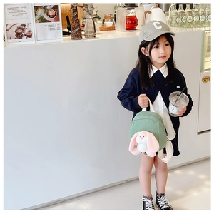 Detail of green kids backpack featuring a cute long-eared plush bunny doll on front
