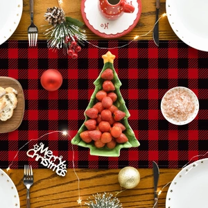 Detail view of red and black checkered Christmas table runner with festive dinnerware