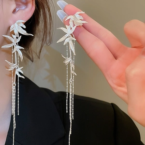 Detailed close-up of silver bamboo leaf tassel earrings on a model showing drape