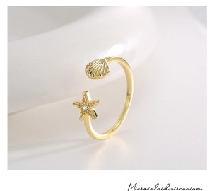 Detaillierte Makroaufnahme eines goldenen Rings mit Muschel und Zirkon-Seestern-Motiv