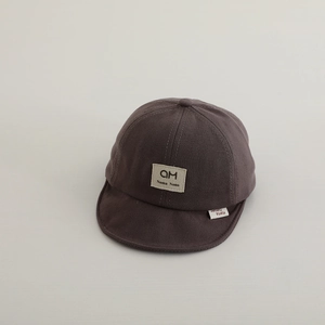 Close-up of soft-brimmed cotton baby baseball cap in coffee brown with logo patch detail