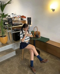 Polo a righe retrò con gonna a pieghe blu navy e borsa Boston in pelle marrone