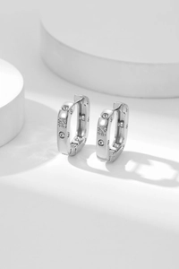 Macro shot of silver zircon hoop earrings with square gemstones on white background