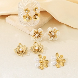 Macro detail of four vintage floral earrings featuring 18K gold plating and inlaid pearls
