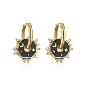 Detalle de pendientes chapados en oro 18K con esmalte negro y motivos de estrella y luna