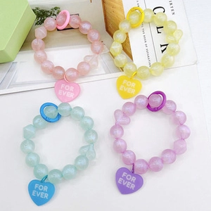Detail of beaded bracelets in pastel colors with heart charms featuring FOR EVER text
