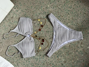 Detail of grey textured ruched bikini featuring gold layered chains and metal sequins