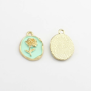Detail of oval rose charm with mint green enamel inlay and textured golden metal back