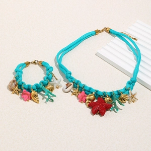 Detail of blue braided nautical necklace and bracelet set with gold seashell charms