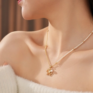 Close-up of a gold starfish necklace with a pearl and zircons worn by a female model