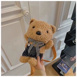 Detail of cute teddy bear plush bag featuring blue denim overalls and checkered bow tie