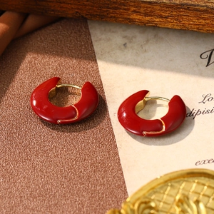Macro shot of red enamel C-shaped hoop earrings with vintage gold metal accents