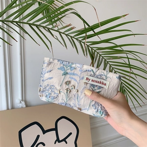Detailed close-up of floral jacquard embroidery on a mini white cream cosmetic bag
