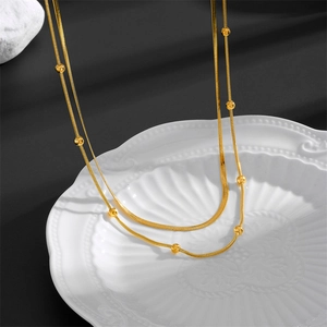 Détail d'un collier double épaisseur doré avec chaîne serpent plate et perles décor