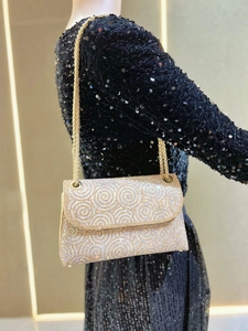 Close-up of golden rhinestone evening bag featuring wave patterns and metal chain strap