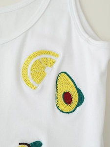 Close-up of ribbed white top featuring sequined lemon and avocado embroidery details