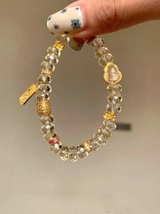 Gros plan du bracelet en perles de cristal avec breloque gourde et plaque gravée dorée