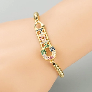 Close-up of golden bead bracelet featuring a MOM letter charm with colorful stones