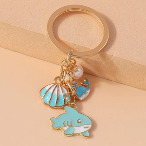 Detailed view of ocean theme keychain with blue whale, pearl and shell charms on gold ring
