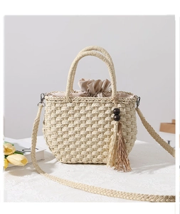 Detail of hand-woven straw bag with wooden bead tassel and drawstring closure