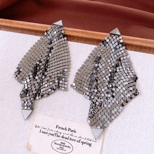 Détail de boucles d'oreilles à paillettes gunmetal avec texture en maille métallique sur plateau