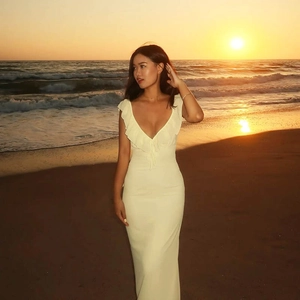 Close-up of white ruffled deep V-neckline dress on a sunset beach setting