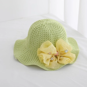 Detail of light green woven straw sun hat with large yellow organza bow and floral accents