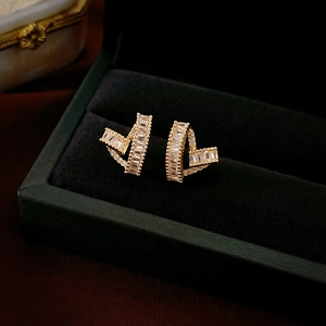 Macro detail of gold-plated heart earrings with T-cut zircon in a black jewelry box