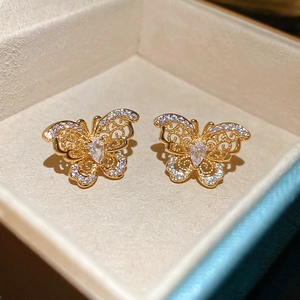 Close-up of gold plated butterfly stud earrings with zircon crystals on beige velvet