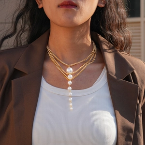 Detail showing multi-layer gold pearl necklace with tiered chains and fringe drops