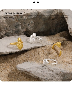 Detailed macro view of brushed gold and silver double heart adjustable rings on a rock surface