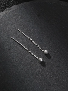 Minimalist silver chain drop earrings with spherical pendants on a textured stone surface