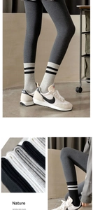 Detail of grey ribbed leggings paired with black and white striped high tube socks