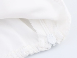 Gros plan sur la fermeture éclair invisible et la dentelle blanche du crop top