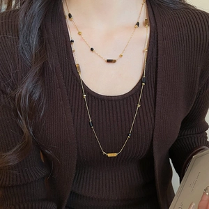 Detail of vintage tiger eye beaded layered necklace on a brown ribbed knit sweater