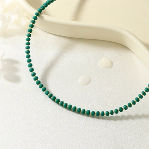 Macro detail of handmade emerald green beads and gold metal spacers on a white tray