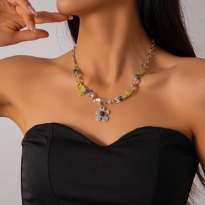 Détail d'un collier de perles argentées avec perles colorées et pendentif fleur rouge