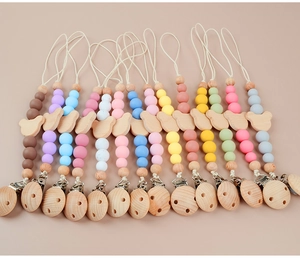 Flat lay of colorful silicone pacifier clips with cute wooden bear beads in various shades