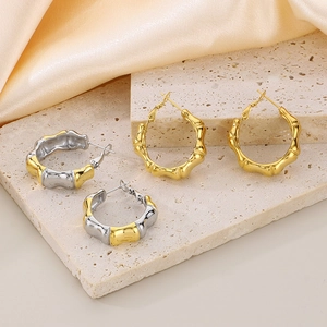 Bamboo style 18K gold-plated and mixed-metal hoop earrings on elegant silk background