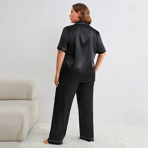 Short sleeve black satin pajama set with contrast white piping for women in home setting