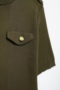 Detailed macro view of olive green ribbed knit fabric with pocket flap and gold button
