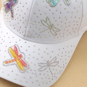 White cotton baseball cap featuring colorful rhinestone dragonflies and a shimmering finish